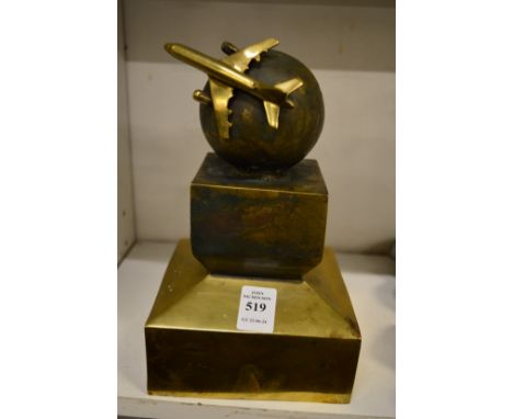 An unusual cast brass model of an aeroplane flying around a globe.