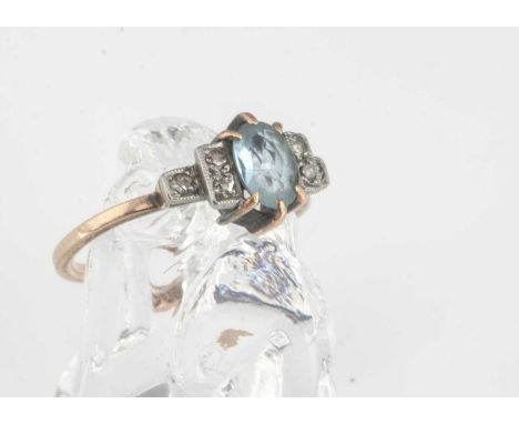 An Art Deco aquamarine and diamond dress ring, the oval aqua in step cut shouldered setting, on yellow metal shank, ring size