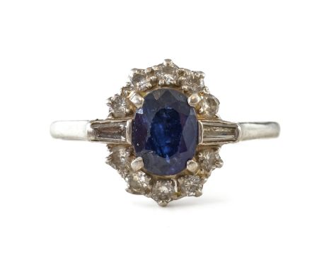 A SAPPHIRE AND DIAMOND OVAL CLUSTER RINGClaw set with the oval cut sapphire at the centre, between tapered baguette diamond s