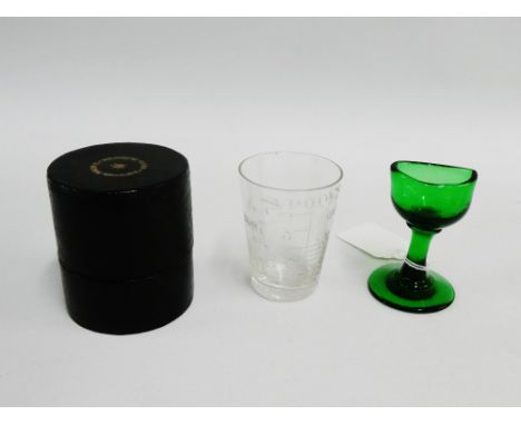 Early 19th century green glass eye bath and a cased medicine glass with etched measuring scale, (2) 