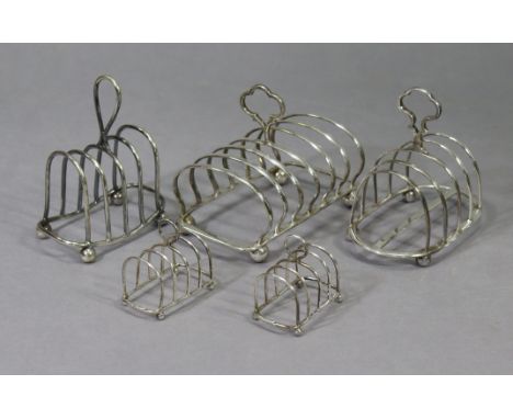 A pair of Edwardian small silver four-division toast racks, 2¾” wide, Chester 1909 by Haseler Bros; &amp; three silver plated