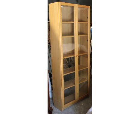 A light oak-finish tall standing cabinet fitted five shelves enclosed by a pair of glazed doors, 31½” wide x 79½” high x 11¾”