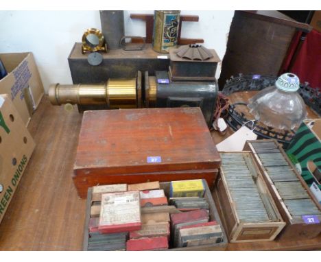 A Victorian brass and tin magic lantern with two lenses with rack focus, tin case and a large number of glass slides