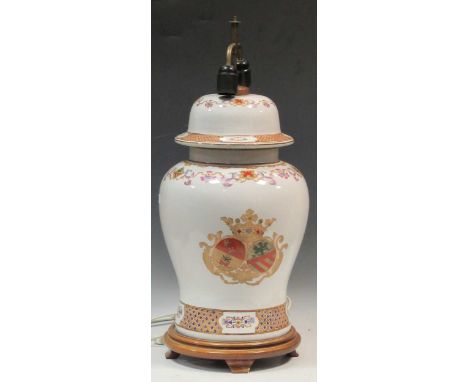 A large ceramic baluster lamp enamelled with a crest on a turned wood stand, approx 65cm high