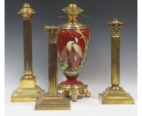 A Victorian brass and porcelain oil lamp, the body painted with a crane, 59cm high; four brass oil lamp bases, tallest 42cm h