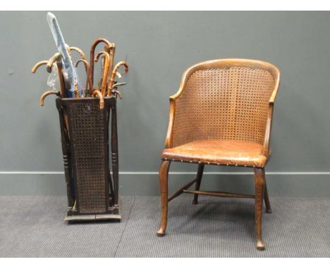 A cane-backed chair with a leather seat and a stick stand