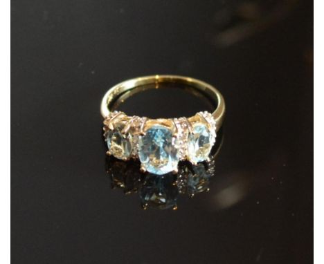 A Yellow Gold Blue Topaz And Diamond Ring set with three oval blue topaz inter-spaced with diamonds within a pierced setting 