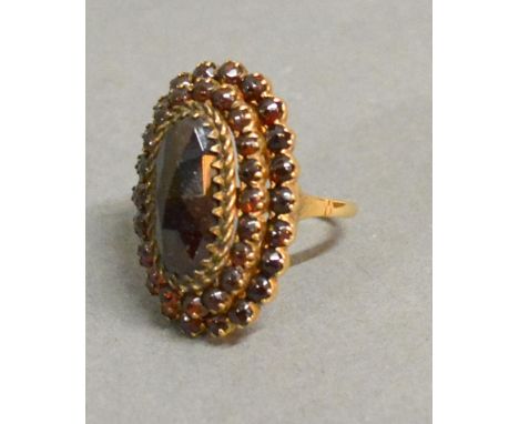 A 14ct. Gold Garnet Set Cluster Ring Of Oval Form With Tiered Rows Of Garnets 