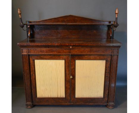 A William IV Burr Oak Chiffonier With A Shelf Back above two frieze drawers and two fabric pleated doors, raised upon low tur