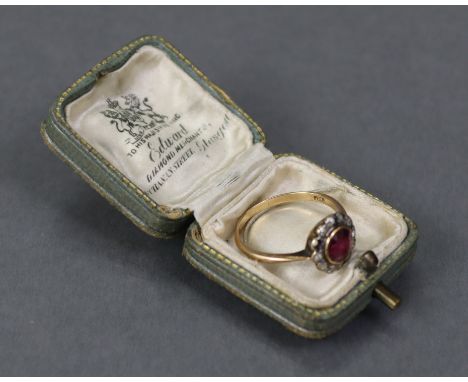 An 18ct. gold ring set round-cut ruby within a border of twelve small diamonds (one missing; size: M/N; (2.1gm).