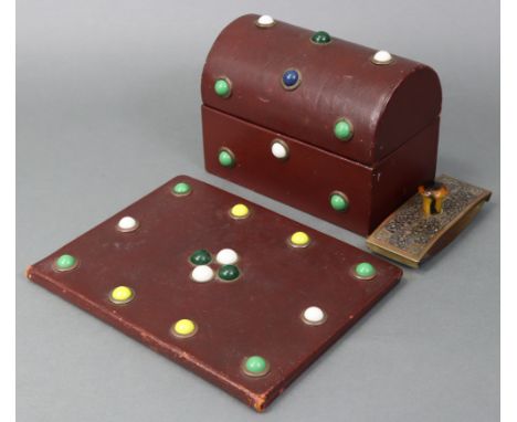 A dome-top stationery box covered in dark red morocco, the hinged lid &amp; front inset with coloured glass roundels; a simil