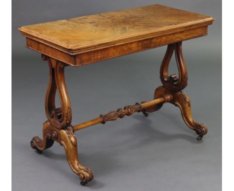 A Victorian figured walnut card table with moulded edge to the fold-over rectangular top inset green baize, on carved lyre su