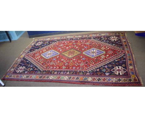 Caucasian style wool carpet, central panel of three lozenges, red and blue field with multi-coloured detail, 2.7 x 1.75m