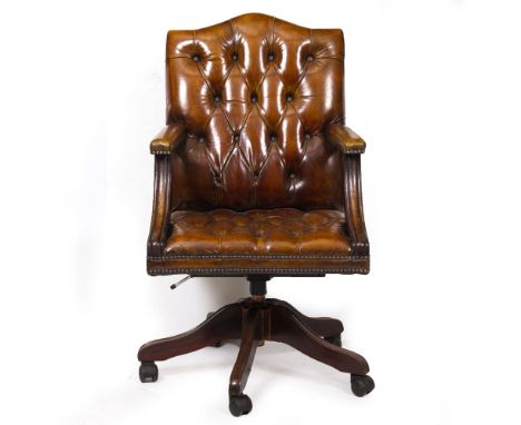 A BROWN LEATHER BUTTON UPHOLSTERED DESK CHAIR in the Georgian style, rotating mechanism and splaying legs terminating in plas