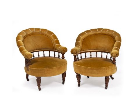 A PAIR OF LATE VICTORIAN WALNUT FRAMED UPHOLSTERED TUB CHAIRS with turned legs terminating in brass and ceramic casters, each