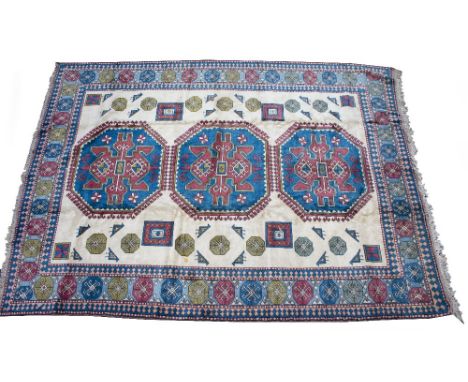 A TURKISH CREAM GROUND SMALL CARPET with a multiple banded border in greens and reds with three octagonal central motifs and 