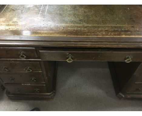 A oak partners desk fitted with 9 drawers on a plinth base