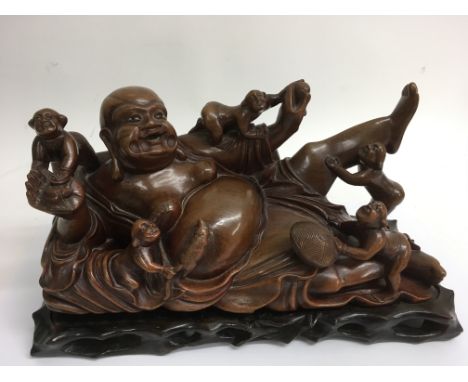 An oriental carved wood model of a reclining Buddha with stand.Approx 14x32cm