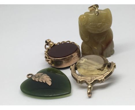Two gold fob pendants with coloured stones together with a pendant in the form of a cat and a jade heart shaped pendant.