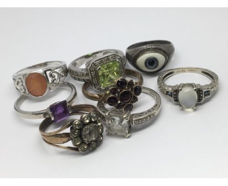 A collection of eight rings having various coloured stones including one set with eye detail.  Various sizes - K-S