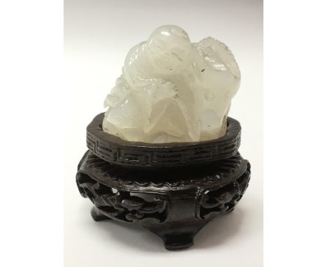 A small, white jade carving of an Immortal on carved wood stand.Approx 4x3.5cm high