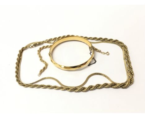A collection of gold and gold tone jewellery comprising a bangle and necklaces.