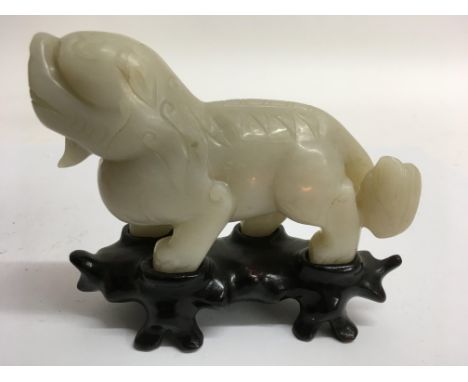 A carved white jade lion on wooden stand.Approx 14x11cm