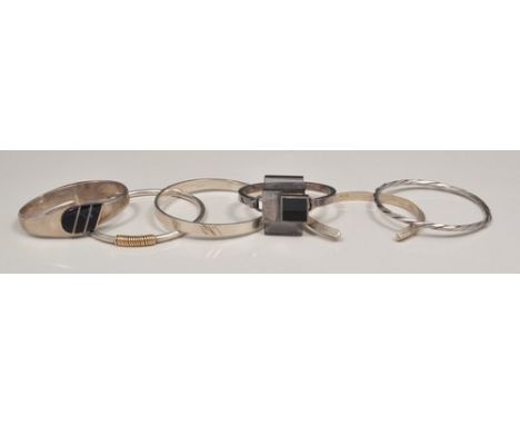 Mexican sterling silver hinged bangle, black onyx faced and five other white metal bangles (6).