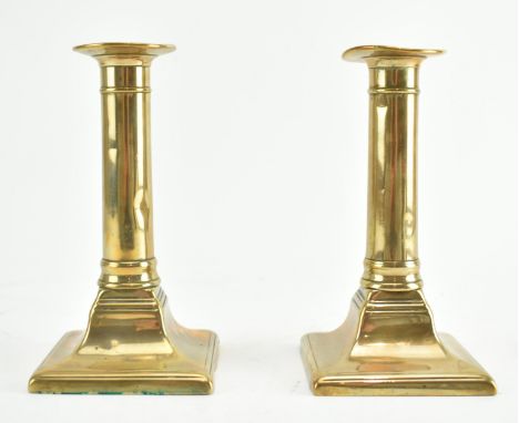 A pair of early 19th century George III brass candlesticks. Each candlestick having a columnar stem rising from a round and c