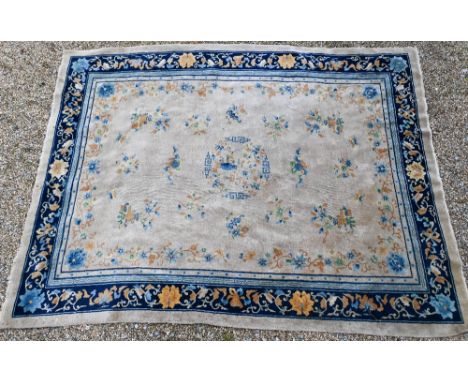 A 1930's Chinese Peking wool carpet, scattered design with bats, auspicious emblems and floral sprays on beige ground, blue f