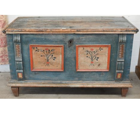 An antique Continental pine trunk, distressed blue paint finish with polychrome floral front panels between decorative carved