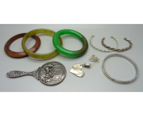 Two jade bangles, a wooden bangle, a white metal mirror, three bangles and a pendant and chain 