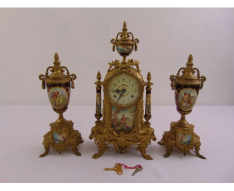 A late 19th century French clock set, gilded metal case with circular enamel dial and applied porcelain plaques flanked by tw