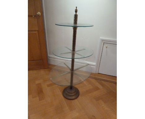 A brass and glass three tier stand with urn finial on raised circular base