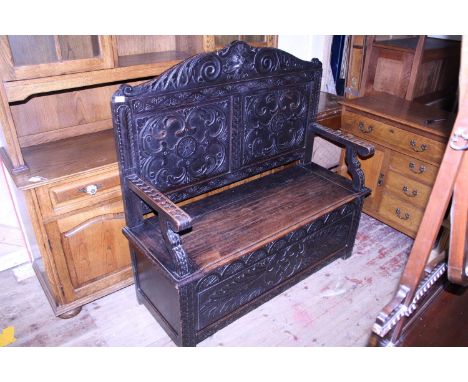 A late 19th century monks bench with storage under seat, hand carved back with Green Man motif approx h115 x w130 x d50cm, sh