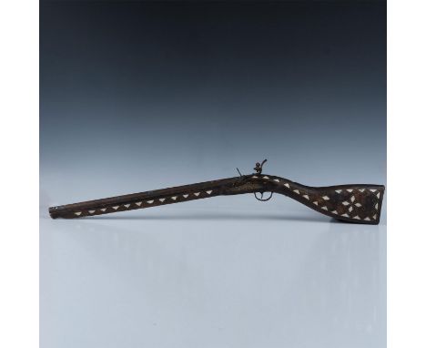With incredible brass wire and mother of pearl inlay detail, the rifle is a dark stained wood with metal pipe gun barrel. The