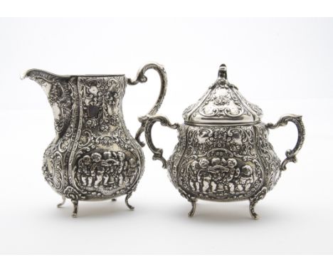 A mid to late 19th century German silver sucrier and milk jug, having relief rococo decoration, sugar basin with cover, 21 oz