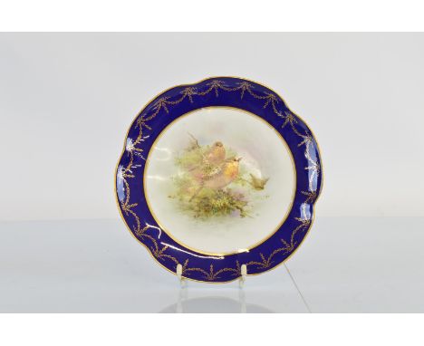 A hand painted Royal Worcester cabinet plate, centred with two robins within a naturalistic setting having a shaped cobalt bl