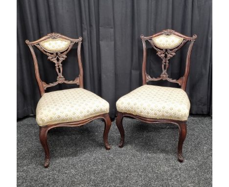 A pair of carved walnut bedroom chairs, having carved and pierced back supports, cabriole legs and shaped front, tapestry uph