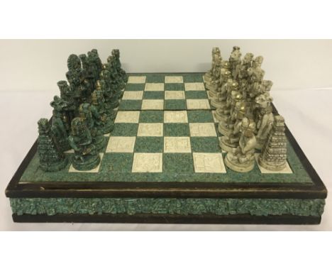 A vintage wooden and resin, highly carved chess board and pieces. Folding chess board makes into box to house the pieces. Set