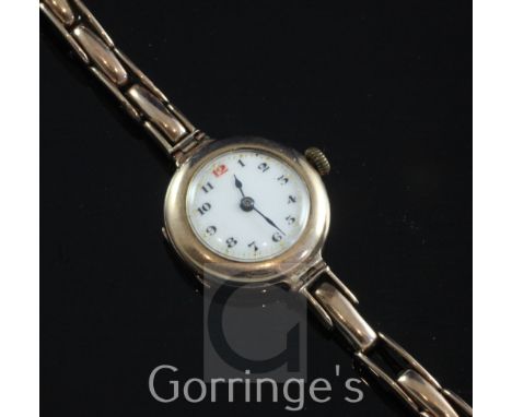 A George V 9ct gold manual wind wrist watch, with Arabic dial, on a 9ct gold flexi-link bracelet (a.f.).