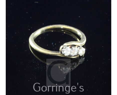 A 18ct gold and three stone diamond ring, the three round cut diamonds in a twist setting, size M.