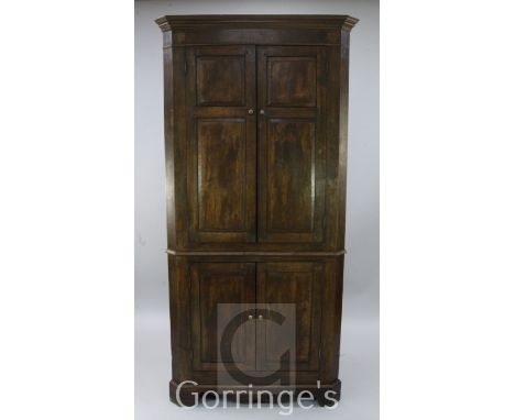 A late 18th century oak standing corner cupboard, fitted with two pairs of fielded panelled doors, raised on bracket feet, wi