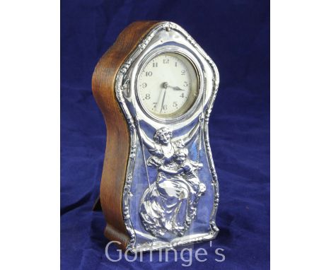 An Edwardian silver mounted wooden mantel timepiece, of waisted form with domed top and Arabic dial, the front silver panel e