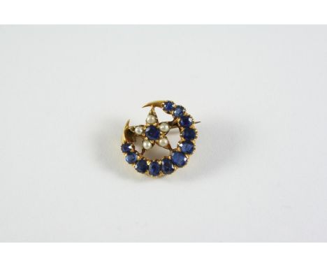 A SAPPHIRE AND PEARL CLOSED CRESCENT AND STAR BROOCH mounted with graduated oval-shaped sapphires and small pearls, in yellow
