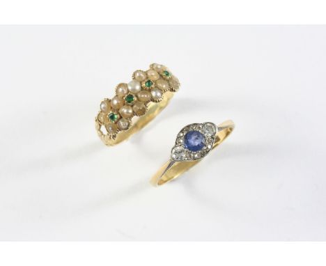 A GEORGIAN EMERALD AND PEARL SET RING formed with four half pearl set flowerheads, each centred with a small emerald, with fo