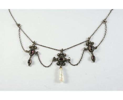 AN ARTS AND CRAFTS GARNET AND SILVER NECKLACE formed with three pendant drops set with oval-shaped garnets suspending a baroq