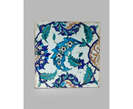 AN IZNIK POTTERY SQUARE TILE, 16TH/17TH CENTURY Boldly decorated in blue, red and green with a geometric design of flowerhead