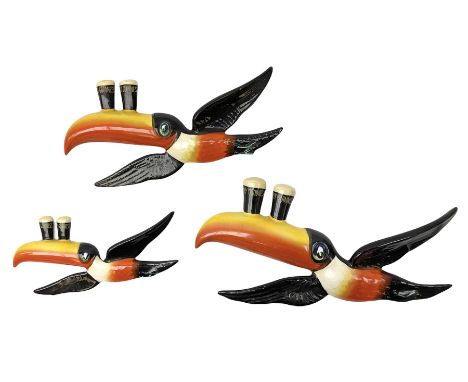 Set of three graduated Carlton Ware ceramic advertising wall plaques modelled as toucans balancing two pints of Guinness on t