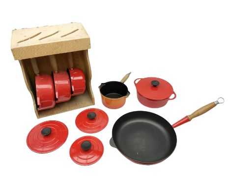 Le Creuset 'Volcanic Orange' cast iron and enamel milk pan with wood handle together with a three piece red cast iron Cousanc